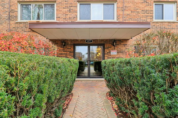 Front view of a brick building entrance with glass doors and address number 477.