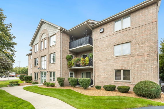 Front view of a three-story brick apartment building with balconies.
