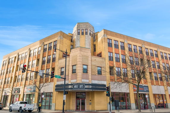 Front view of a multi-story brick building with retail spaces on the ground floor.