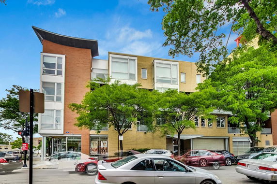 Front view of a modern multi-story building with large windows and a distinct architectural design.