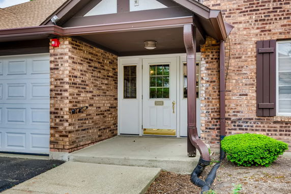 Front view of a brick house with a garage and white entrance door.