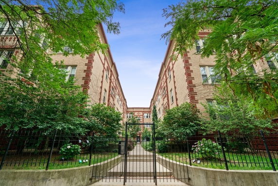 Front view of a multi-story brick building with gated entrance.