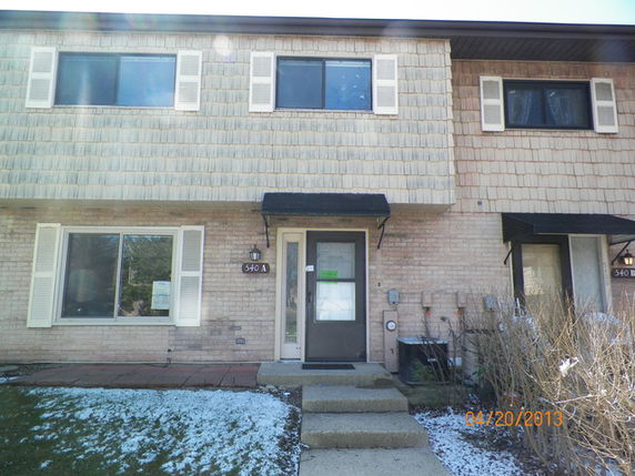 Front view of a two-story townhouse with brick facade and shutters.