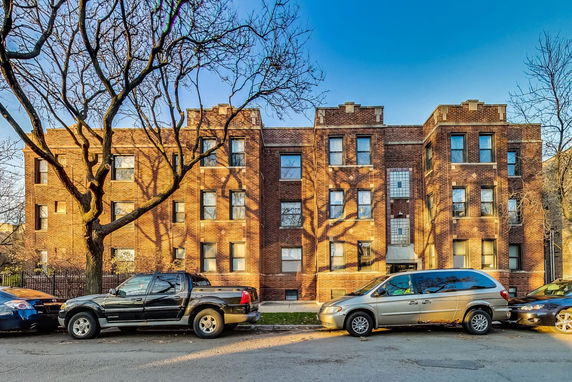 Front view of a brick apartment building with multiple windows.