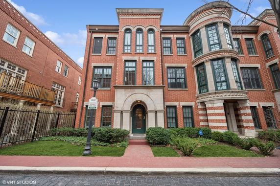 Front view of a multi-story brick building with arched entrance and large windows.