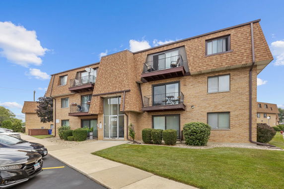Front view of a multi-story brick apartment building with balconies.