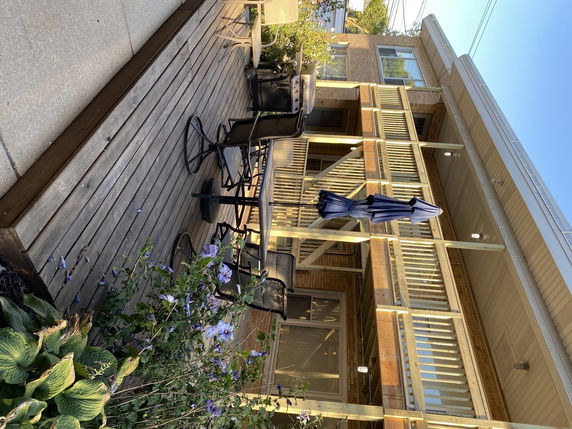 Front view of a house with a wooden deck and outdoor seating area.