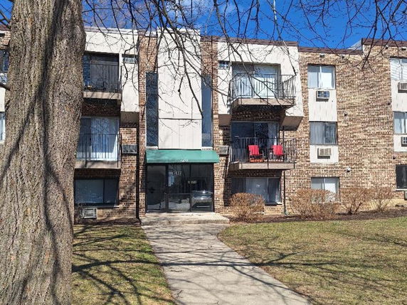 Front view of a three-story brick apartment building with balconies.