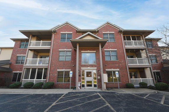 Front view of a three-story brick building with balconies and a central entrance.