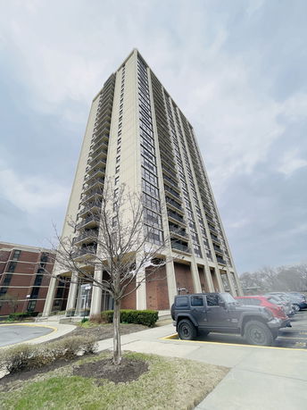 Front view of a high-rise apartment building with balconies and large windows.