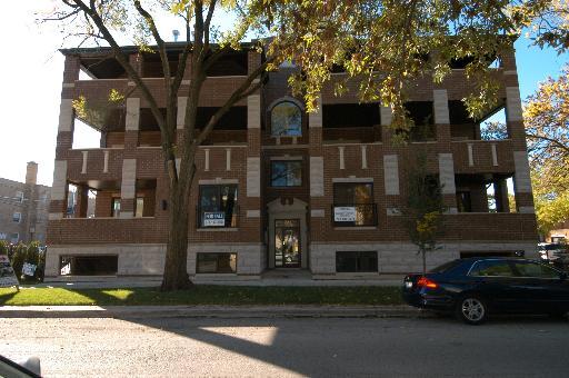 Front view of a multi-story brick building with balconies and large windows.