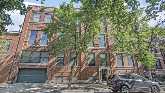 Front view of a multi-story brick building with large windows and a garage entrance.