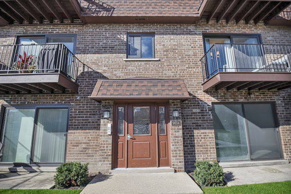 Front view of a brick building with balconies and a central entrance.