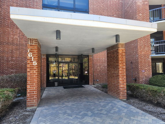 Front view of a building entrance with brick columns and a canopy.