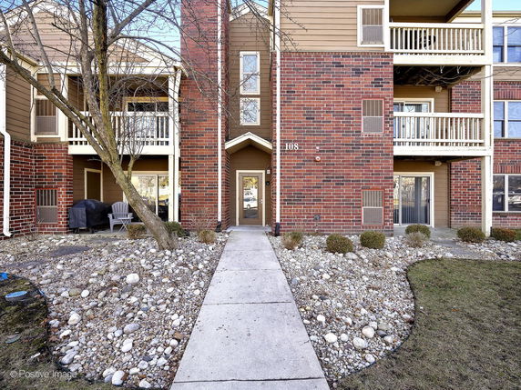 Front view of a multi-story brick apartment building with balconies.