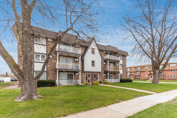 Front view of a multi-story residential building with balconies and brick facade.