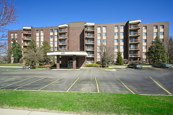 Front view of a multi-story apartment building with a parking area.