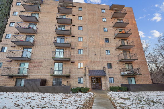 Front view of a multi-story brick apartment building with balconies.