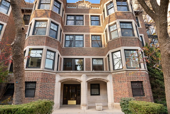 Front view of a multi-story brick building with bay windows and an arched entrance.