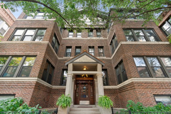 Front view of a multi-story brick building with large windows and an entrance porch.