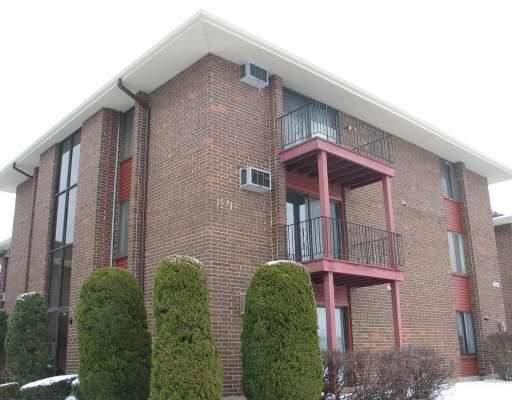 Front view of a three-story brick apartment building with balconies.