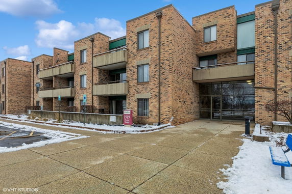 Front view of a multi-story brick apartment building with balconies.