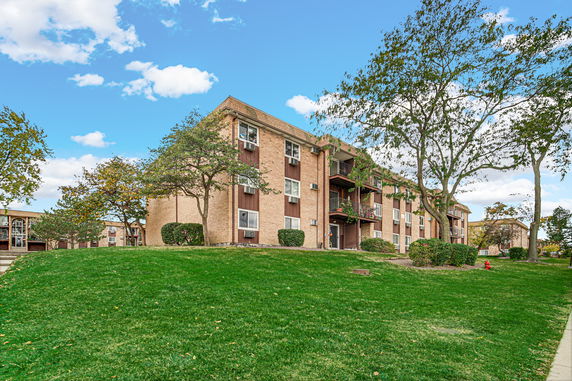 Front view of a multi-story apartment building with balconies and a brick exterior.