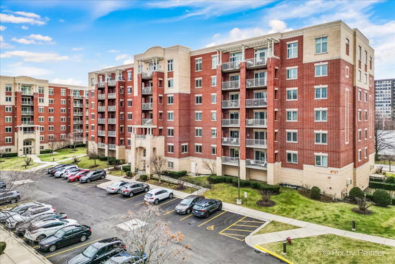 Front view of a multi-story apartment building with red brick facade and balconies.