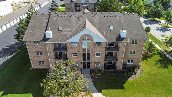 Front view of a three-story brick apartment building with a central entrance and balconies.