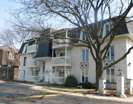 Front view of a multi-story residential building with balconies and a gable roof.