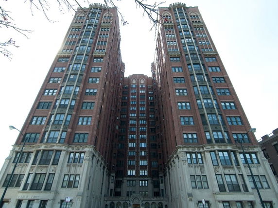 Front view of a tall, multi-story brick building with two prominent towers.