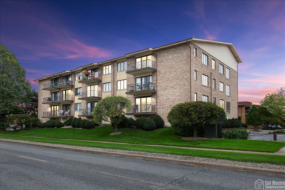 Front view of a multi-story brick apartment building with balconies.