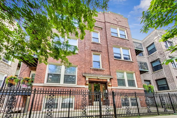 Front view of a multi-story brick building with fenced entry.