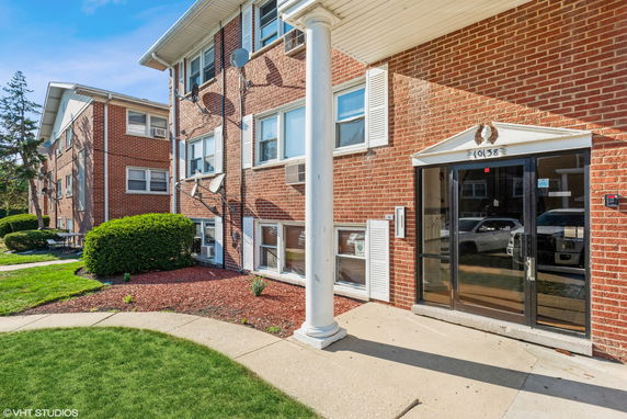 Front view of a brick apartment building with multiple satellite dishes.