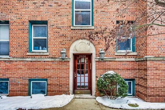 Front view of a brick building with a central door and symmetrical windows.