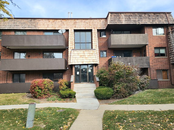 Front view of a multi-story brick apartment building with balconies.