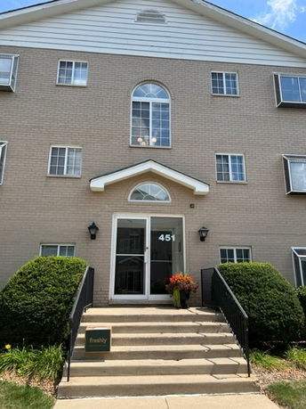 Front view of a multi-story building with a central entrance and steps leading up to it.
