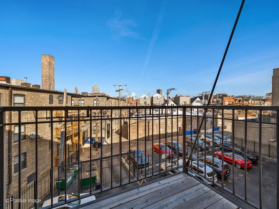 View from a balcony overlooking a parking lot and surrounding buildings.
