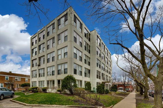 Front view of a multi-story residential building with large windows.