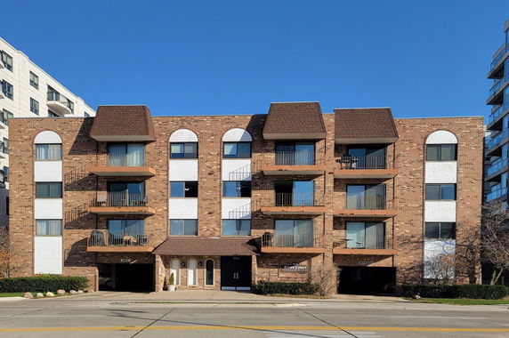 Front view of a multi-story brick apartment building with balconies.