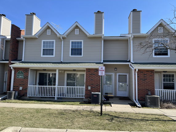 Front view of a two-story residential building with a porch and chimneys.