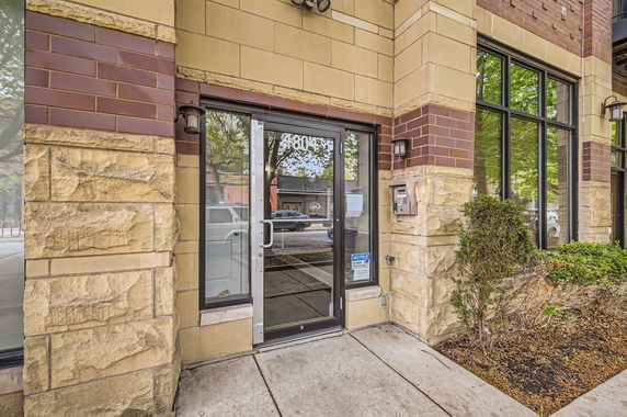 Front view of a building entrance with glass doors and stone facade.