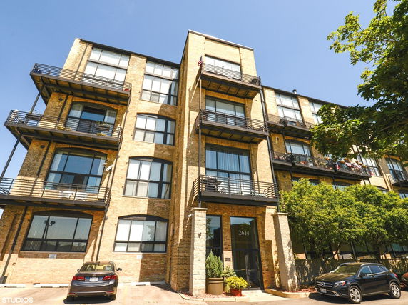 Front view of a multi-story brick apartment building with balconies.