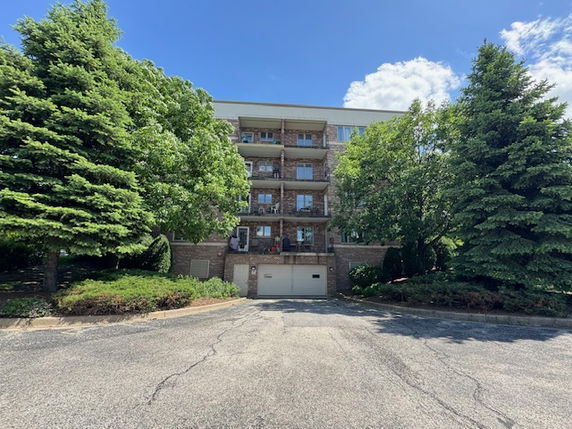 Front view of a multi-story residential building with balconies and an entrance.
