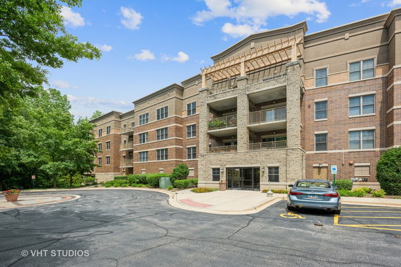 Front view of a multi-story residential building with balconies and a parking area.