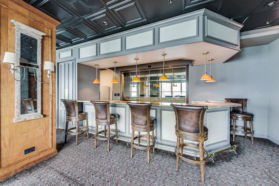 Interior view of a clubhouse bar area with bar stools and pendant lights.