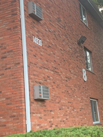Red brick building with air conditioning units attached to the exterior walls.