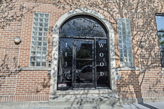 Front view of a building with brick facade and arched glass entry.