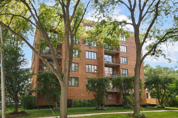 Front view of a multi-story brick apartment building with balconies.