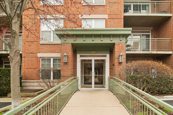 Front view of a brick apartment building with balconies and a glass entrance door.